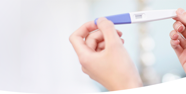 Woman holding a pregnancy test showing two blue lines.